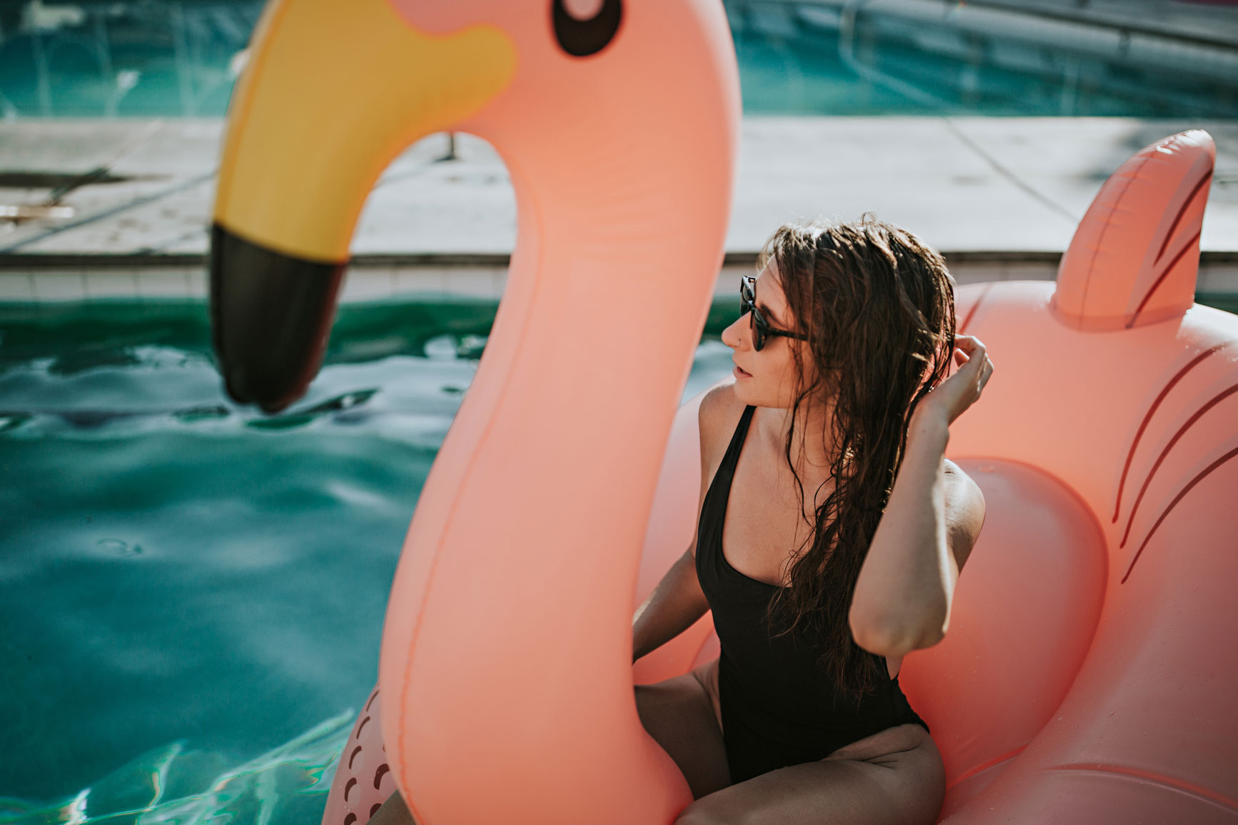 Woman sitting in a flamingo inflatable at the pool